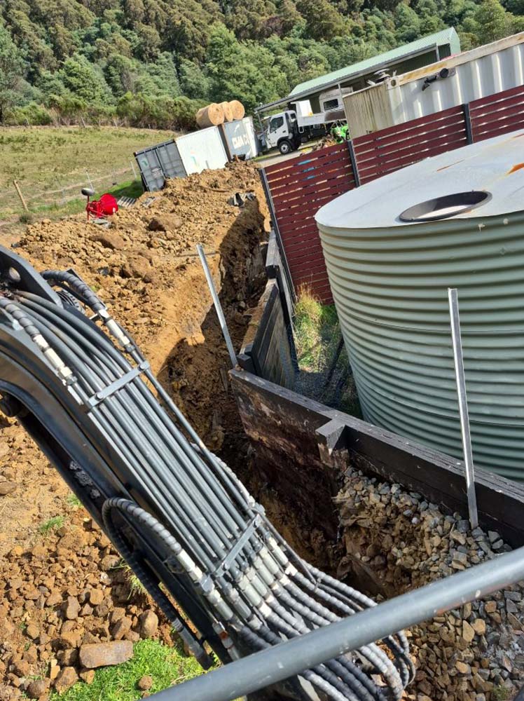 Trench with conduits dug beside a water tank
