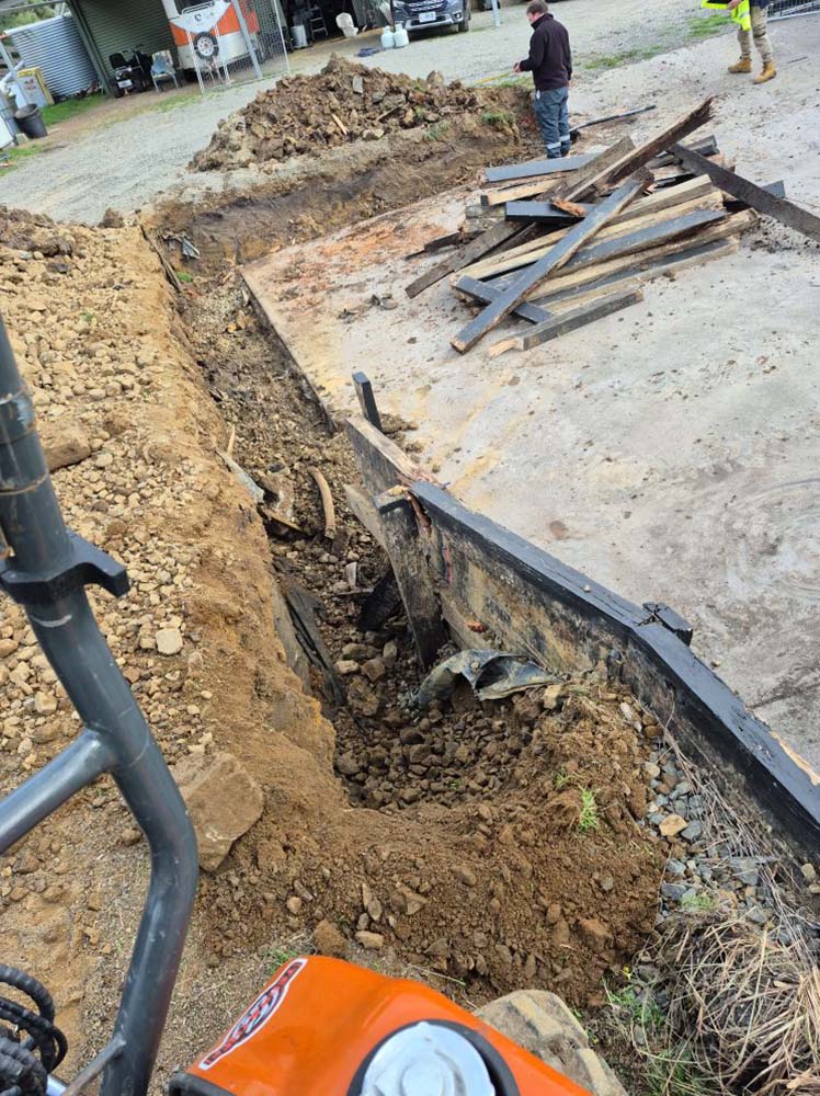 Trench dug along a concrete slab edge, seen from an excavator